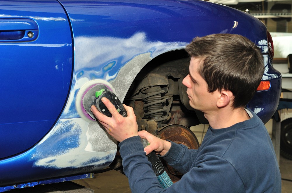 Car body worker sanding old paint..